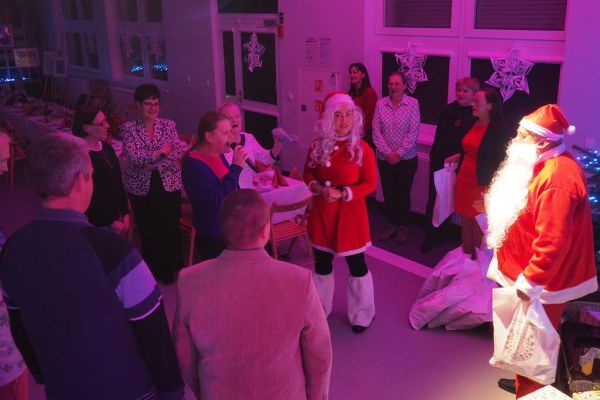 Mieszkańcy stoją przy mikołaju i śnieżynce razem z panią dyrektor.