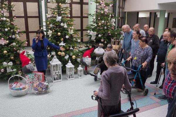 Pani Wójt składa życzenia zgromadzonym mieszkańcom na holu domu.