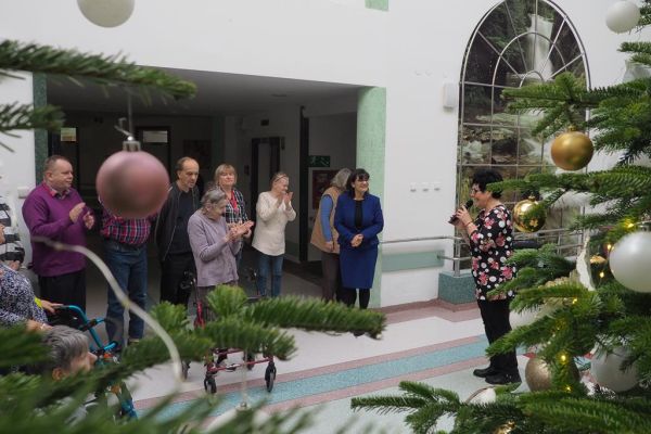 Pani Wójt składa życzenia zgromadzonym mieszkańcom na holu domu.