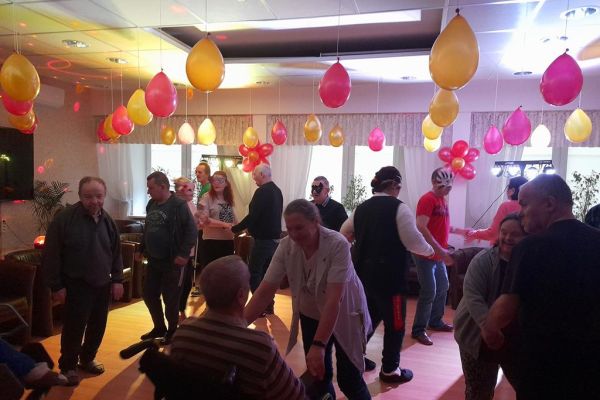 Mieszkańcy tańczą podczas zabawy w kawiarence domu.