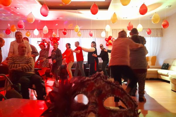 Mieszkańcy tańczą podczas zabawy w kawiarence domu.