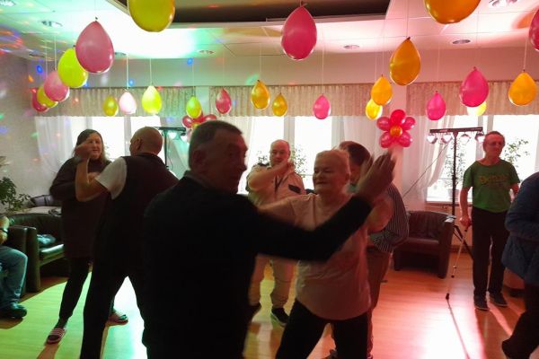Mieszkańcy tańczą podczas zabawy w kawiarence domu.