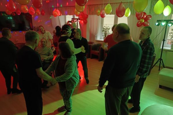 Mieszkańcy tańczą podczas zabawy w kawiarence domu.