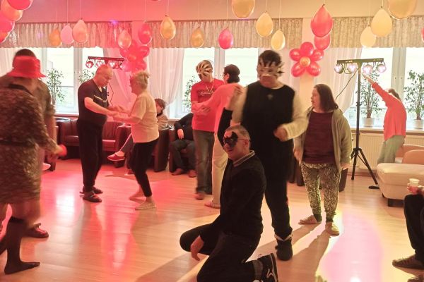 Mieszkańcy tańczą podczas zabawy w kawiarence domu.