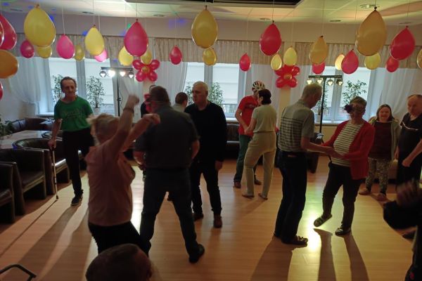 Mieszkańcy tańczą podczas zabawy w kawiarence domu.