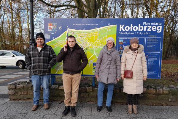 Czworo mieszkańców stoi przy planie miasta Kołobrzeg. miasta 