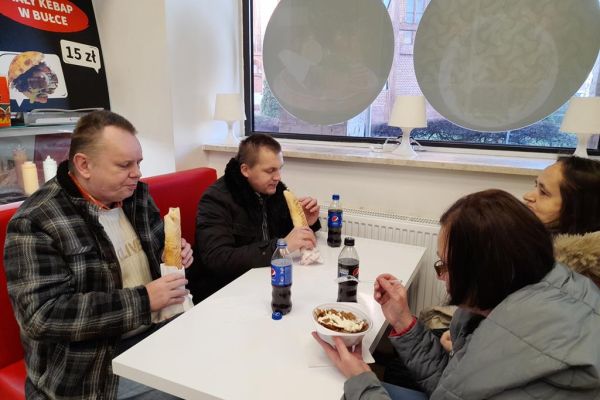 Czworo mieszkańców spożywa jedzenie w restauracji w Kołobrzegu.