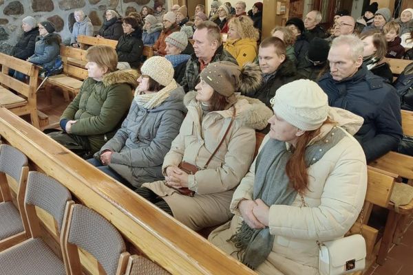 Mieszkańcy wraz z innymi uczestnikami koncertu słuchaja kolęd siedząc w ławce w kościele w Rowach.