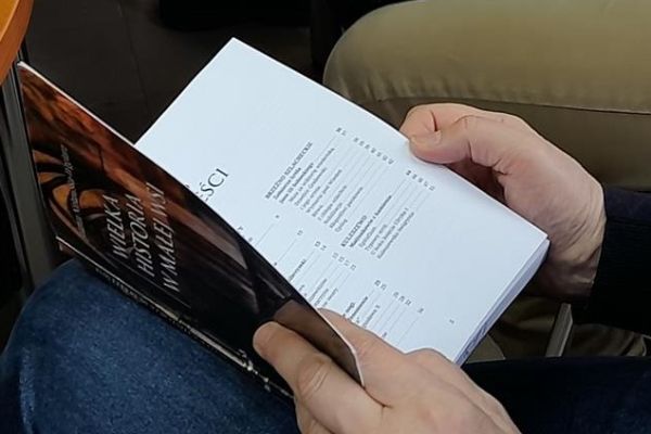 Mieszkaniec trzyma książkę otwartą, ujęcie samych rąk z książką.