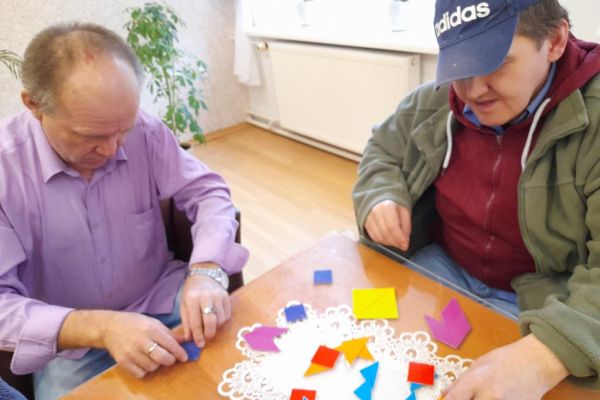 Mieszkańcy układają gry logiczne i myślowe przy stoliku.
