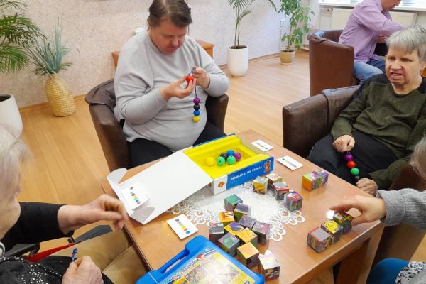 Mieszkańcy układają gry logiczne i myślowe przy stoliku.