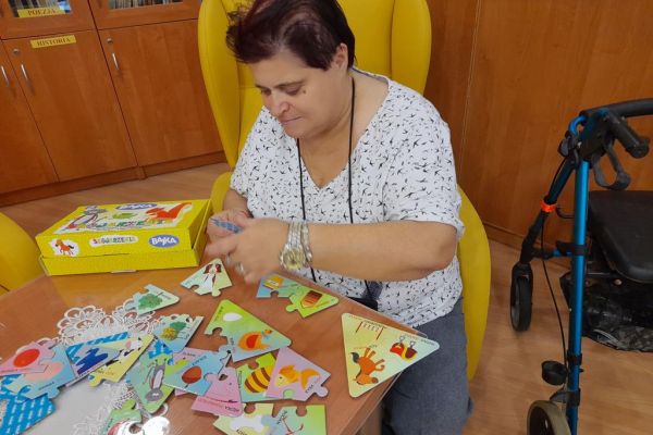 Mieszkanka układa gry logiczne i myślowe przy stoliku.