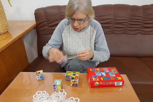 Mieszkanka układa gry logiczne i myślowe przy stoliku.