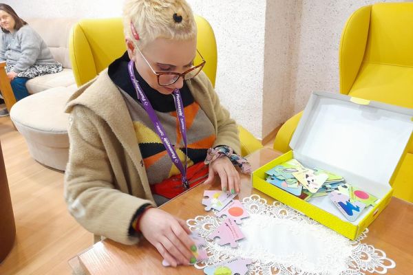 Mieszkanka układa gry logiczne i myślowe przy stoliku.