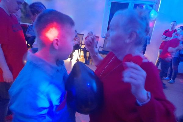 Mieszkańcy wraz z innymi uczestnikami zabawy tańczą z balonem na sali w Przytocku.