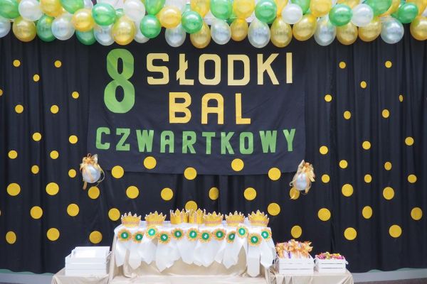 Napis 8 słodki bal czwartkowy w kolorach złotego i zielonego na tle czarnej kotary w złote kropki. 