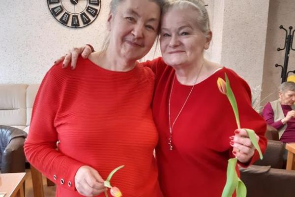 Dwie mieszkanki stoją z kwiatami.