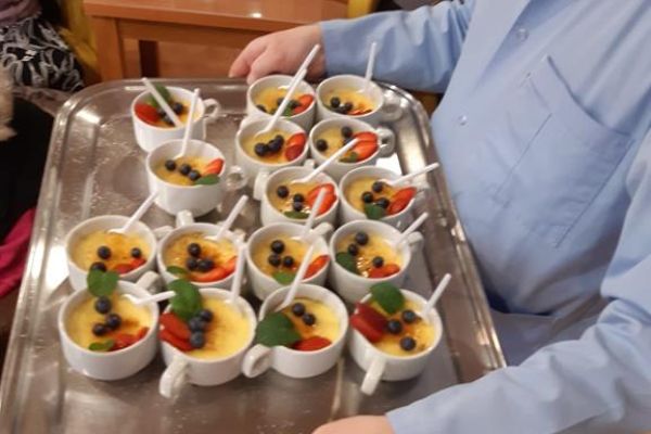 Taca z deserem niesiona przez opiekuna.