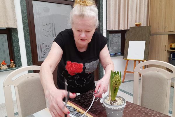 Mieszkanka obcina kawałek tasiemki do kwiatka.