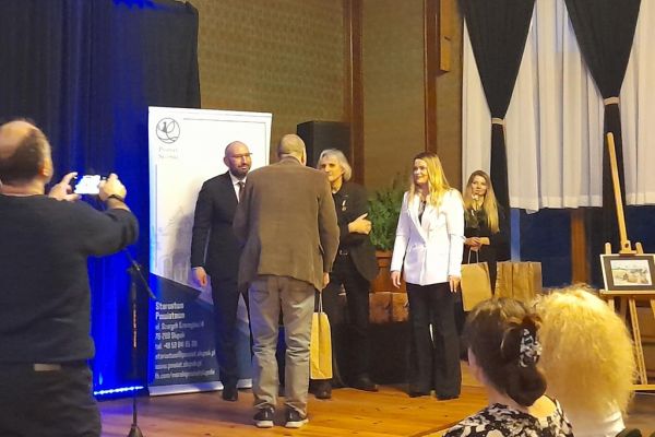 Mieszkaniec odbiera tomik poezji z rąk władz Powiatu Słupskiego.