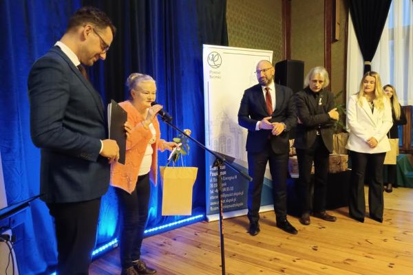 Mieszkanka odbiera tomik poezji z rąk władz Powiatu Słupskiego.