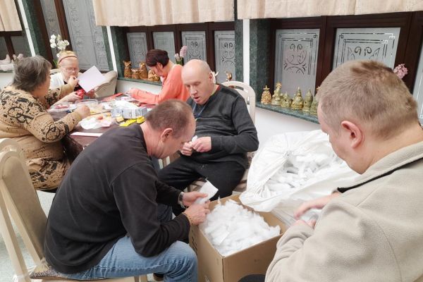 Mieszkańcy wykonują różne czynności siedząc przy stolikach w terapii.