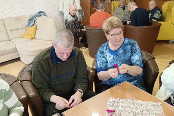 Mieszkańcy wraz z uczestnikami UTW z Redzikowa wykonują ozdoby siedząc przy stolikach w kawiarence na terenie DPS  w Lubuczewie.