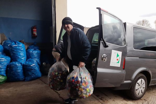 Mieszkaniec wynosi z auta nakrętki w dużych workach.