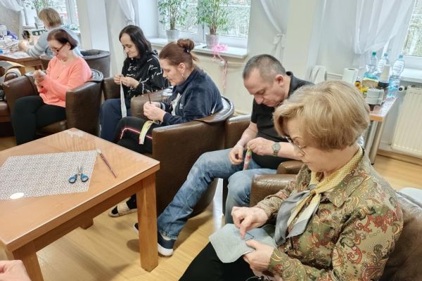 Mieszkańcy wraz z uczestnikami UTW w Redzikowie wycinają wzory z materiału i szyją.