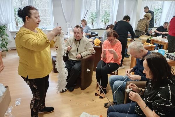 Mieszkańcy wraz z uczestnikami UTW w Redzikowie wycinają wzory z materiału i szyją.