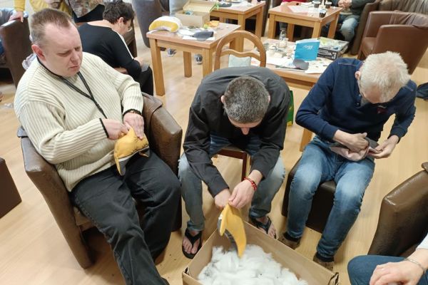 Mieszkańcy wraz z uczestnikami UTW w Redzikowie wycinają wzory z materiału i szyją.