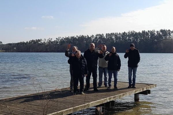 Grupka mieszkańców na pomoście jeziora.