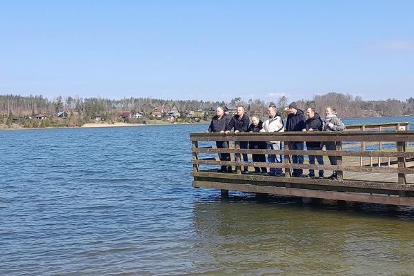 Grupka mieszkańców na pomoście jeziora.
