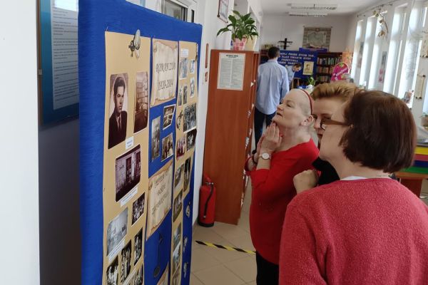 Mieszkańcy w bibliotece przed tablicą upamiętniajaca Romana Zuba.