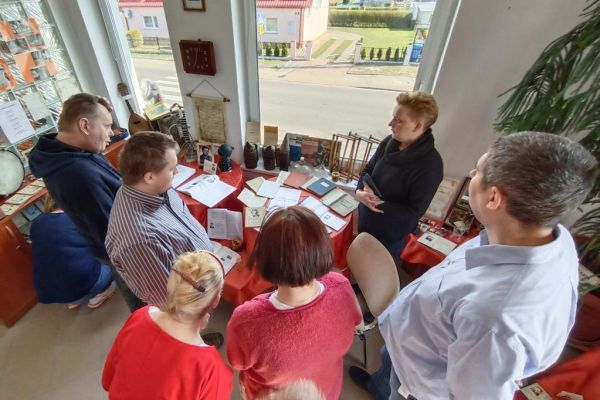 Mieszkańcy w bibliotece przy stolikach omawiają książki.