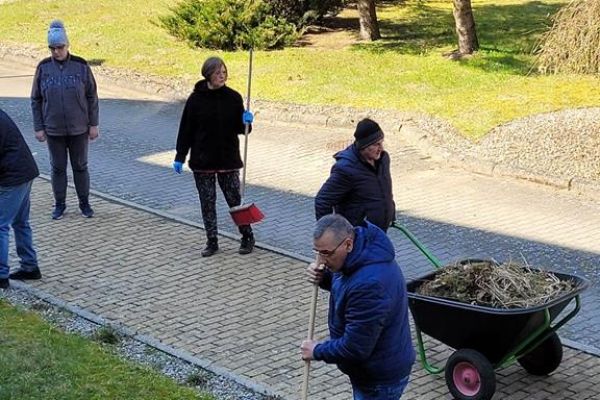 Mieszkańcy grabia i zamiatają teren wokół Domu.