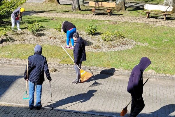 Mieszkańcy grabia i zamiatają teren wokół Domu.