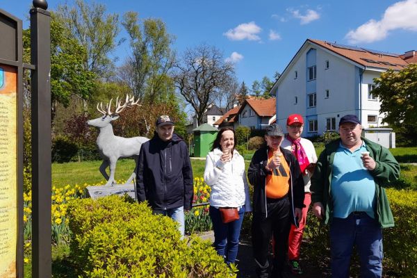 Mieszkańcy zwiedzają Złotów. Stoją przy rzeźbie jelenia.