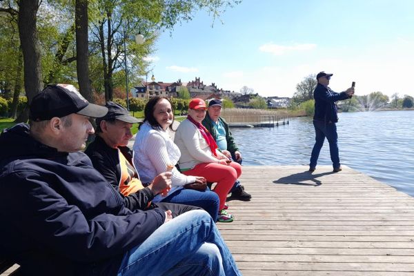 Mieszkańcy zwiedzają Złotów. Siedzą na ławkach przy jeziorze.