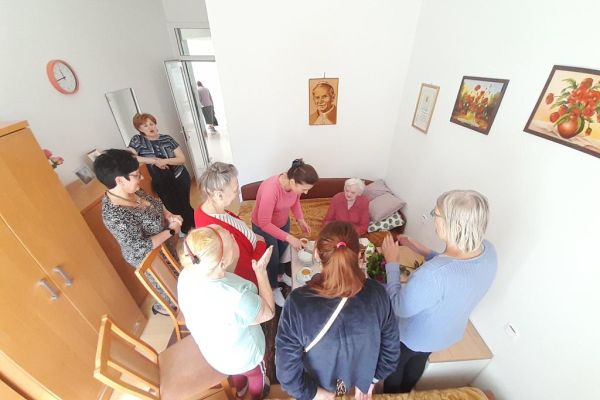 Cztery mieszkanki i troje pracowników śpiewają sto lat.