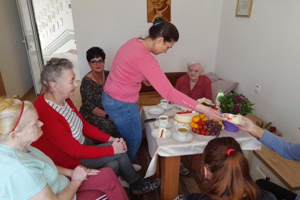 Pracownica dzieli tort i rozdaje na talerzykach.