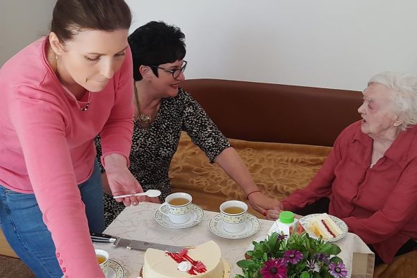 Pani Dyrektor trzyma za rękę w geście życzeń jubilatkę.