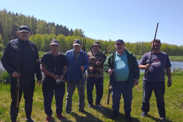 Sześciu mieszkańców stoi z wędkami.