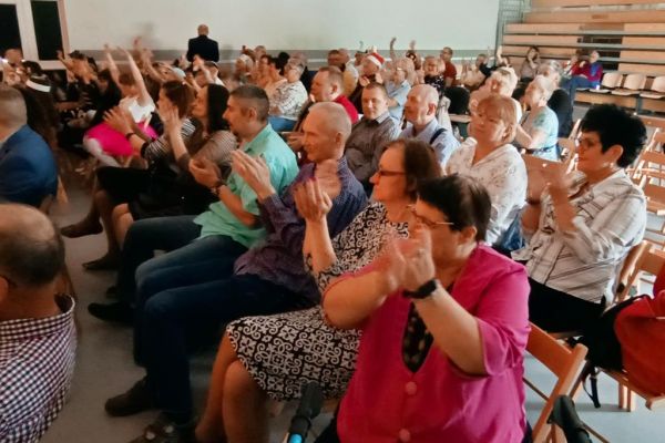 Mieszkańcy klaskają na siedząco podczas wydarzenia.