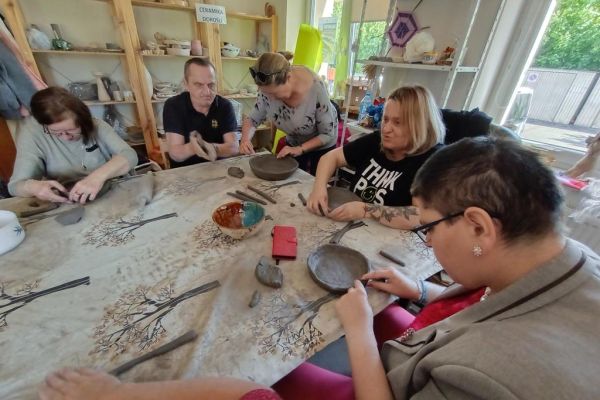 Mieszkańcy wraz z uczestnikami UTW z Redzikowa lepią poidełka z gliny.