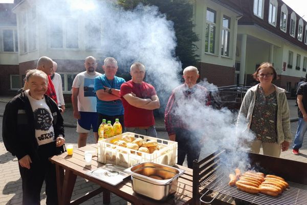 Mieszkańcy stoją przy grillu.