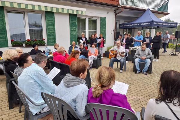 Uczestnicy pikniku śpiewają siedziąc na tarasie.