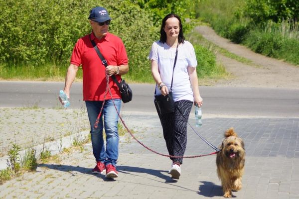 Mieszkanka wraz z uczestnikiem UTW z Redzikowa spaceruje z psem.