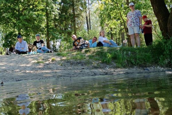 Mieszkańcy leżą na polanie przy jeziorze.