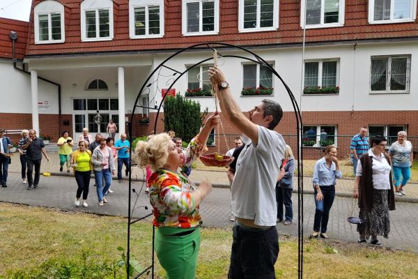 Mieszkańcy wraz z uczestnikami UTW z Redzikowa wieszają poidełka dla ptaków na dworze.